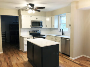 Home remodeling project featuring a kitchen with white cabinets, white quartz countertops, and a blue island