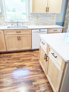 Home remodeling project featuring a kitchen with natural maple cabinets and white quartz countertops