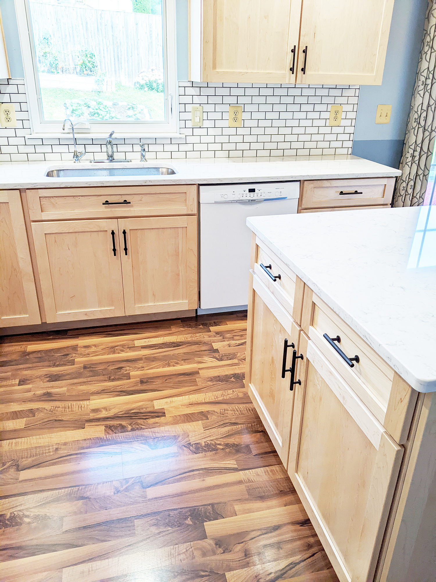 Home remodeling project featuring a kitchen with natural maple cabinets and white quartz countertops